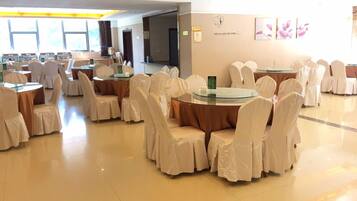 A banquet hall with round tables and chairs, a large window, and a wall with a motivational quote.