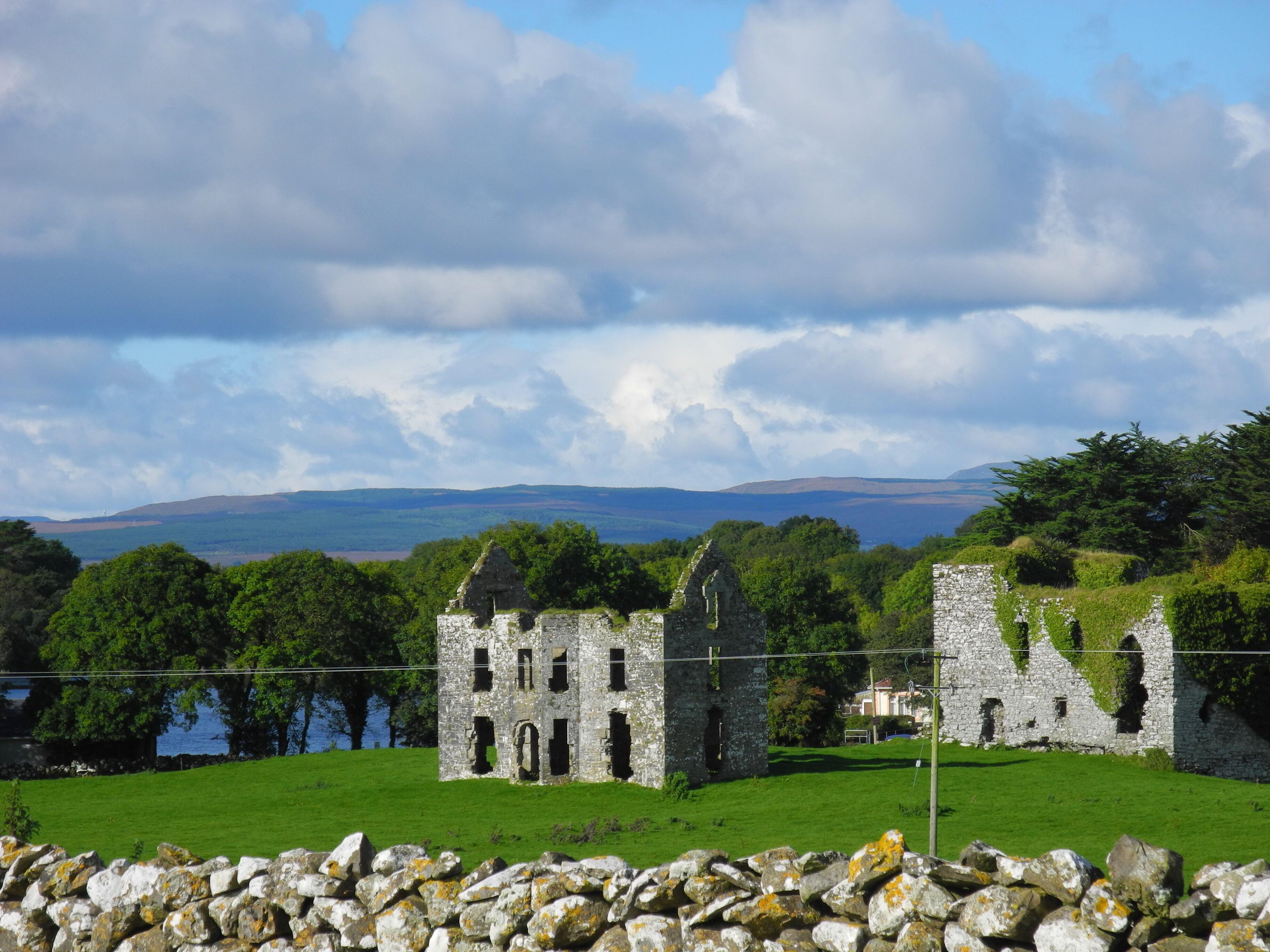 An ancient stone structure with multiple arches and a grassy foreground.