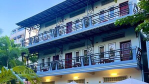 A multi-story hotel with a pool area featuring lounge chairs and umbrellas. - The Local Time Village (Siem Reap)