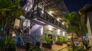 A multi-story hotel with outdoor seating and a staircase leading to the upper levels. - The Local Time Village (Siem Reap)