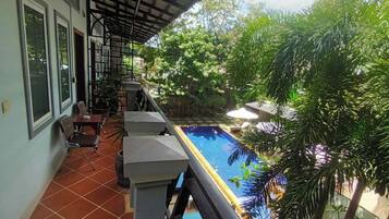 A balcony with a pool, chairs, and a table.
