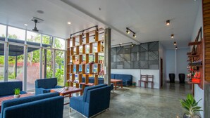 A spacious indoor area with blue seating, wooden shelves, and a patterned wall. - The Local Time Village (Siem Reap)