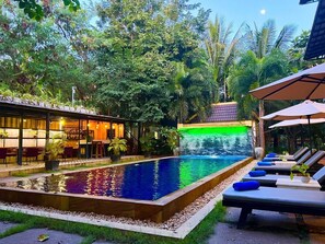 A pool area with lounge chairs and a waterfall feature.