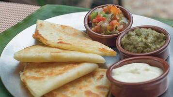 A plate with three pieces of flatbread and two small bowls of dips.