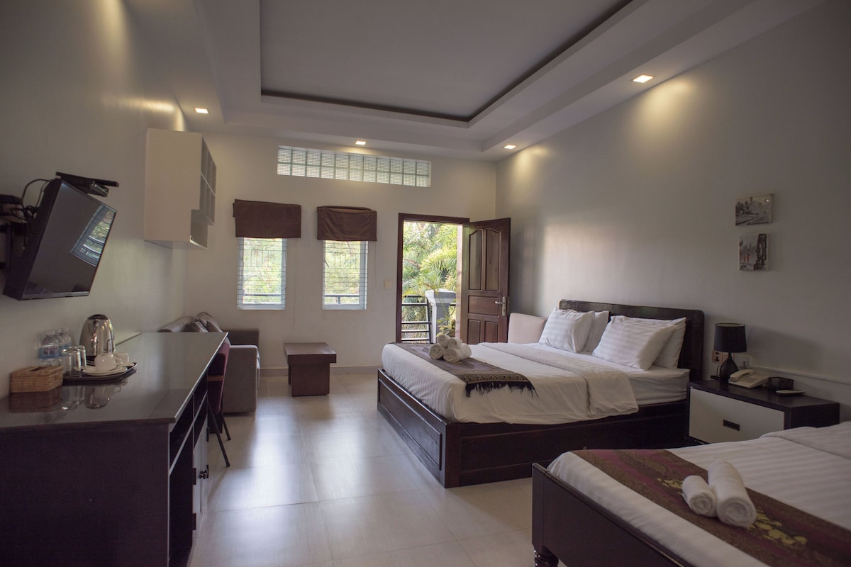 A hotel room with a bed, bedside table, desk, and a television.
