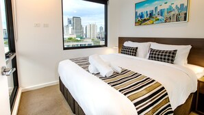 Quarto de hotel com uma cama grande, vista para a cidade e um quadro na parede.