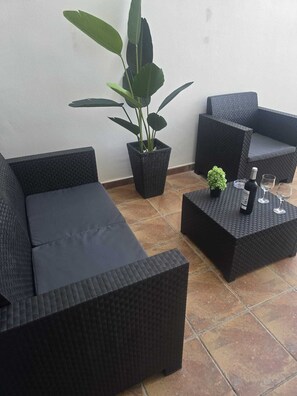 A patio area with two black wicker sofas, a small potted plant, a table with a bottle and glasses, and a tiled floor. - Beautiful new house, with terrace / solarium in Arona (Arona)