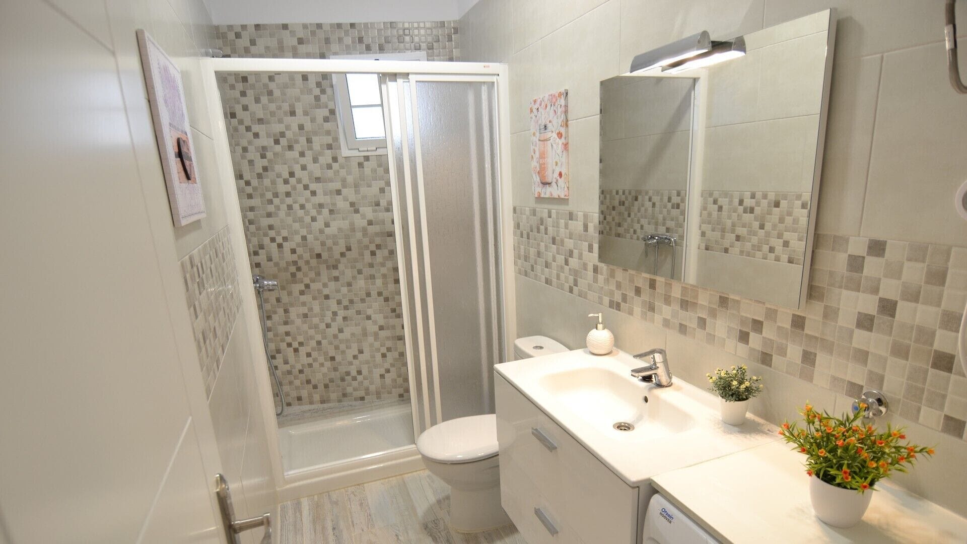 A modern bathroom with a shower, toilet, sink, and a large mirror.