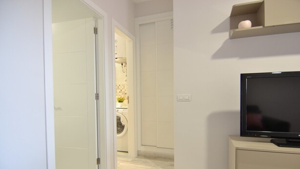 A modern bathroom with a toilet, sink, and shower. There is a television on a cabinet to the right. - Beautiful new house, with terrace / solarium in Arona (Arona)
