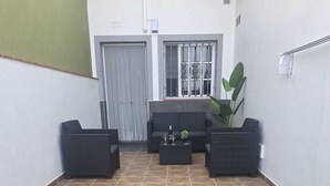 A courtyard with a small artificial grass area, a seating arrangement with sofas and a coffee table, and a door with a window and decorative ironwork. - Beautiful new house, with terrace / solarium in Arona (Arona)