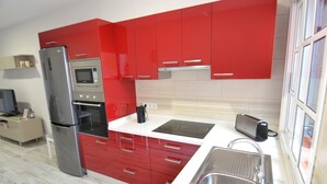 A modern kitchen with red cabinets, a stainless steel refrigerator, a microwave, and a toaster. - Beautiful new house, with terrace / solarium in Arona (Arona)