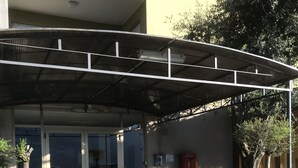 A building entrance with a covered walkway, glass doors, and a red mailbox.