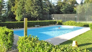 A swimming pool surrounded by lush greenery and a tall fence.