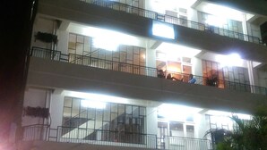 A multi-story building with balconies, a sign reading "New Sunier," and two parked cars in front. - Hotel New Sunder (Indore)