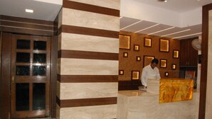 A reception area with a marble reception desk, wooden paneling, and recessed lighting. - Hotel New Sunder (Indore)
