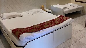 A hotel room with a bed, bedside table, and a small desk with a chair. - Hotel New Sunder (Indore)