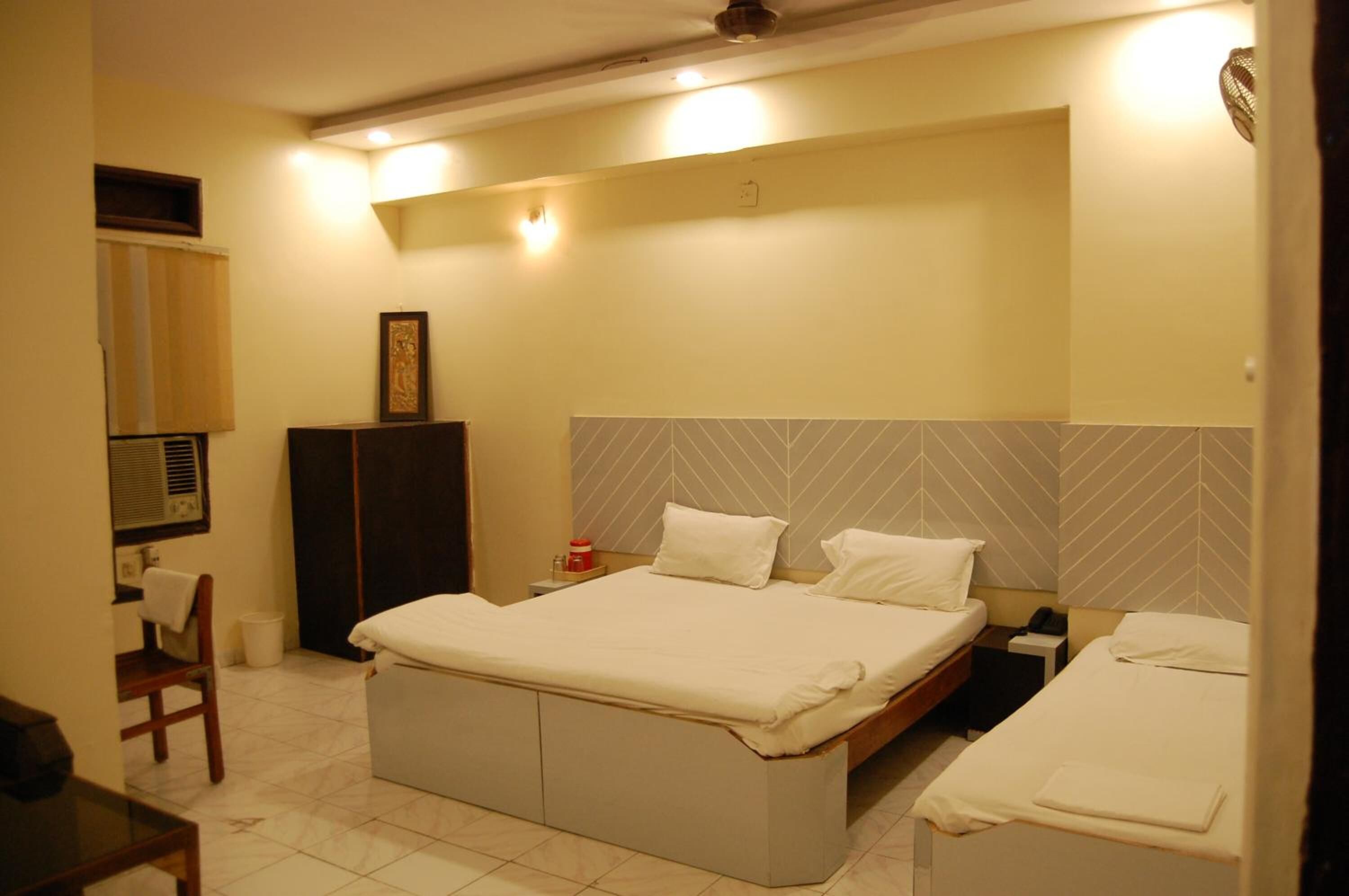 A hotel room with a large bed, a bedside table, a chair, and a wardrobe.