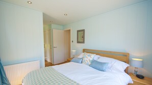 Een slaapkamer met een bed, nachtkastjes, een deur en een aan de muur hangend schilderij.