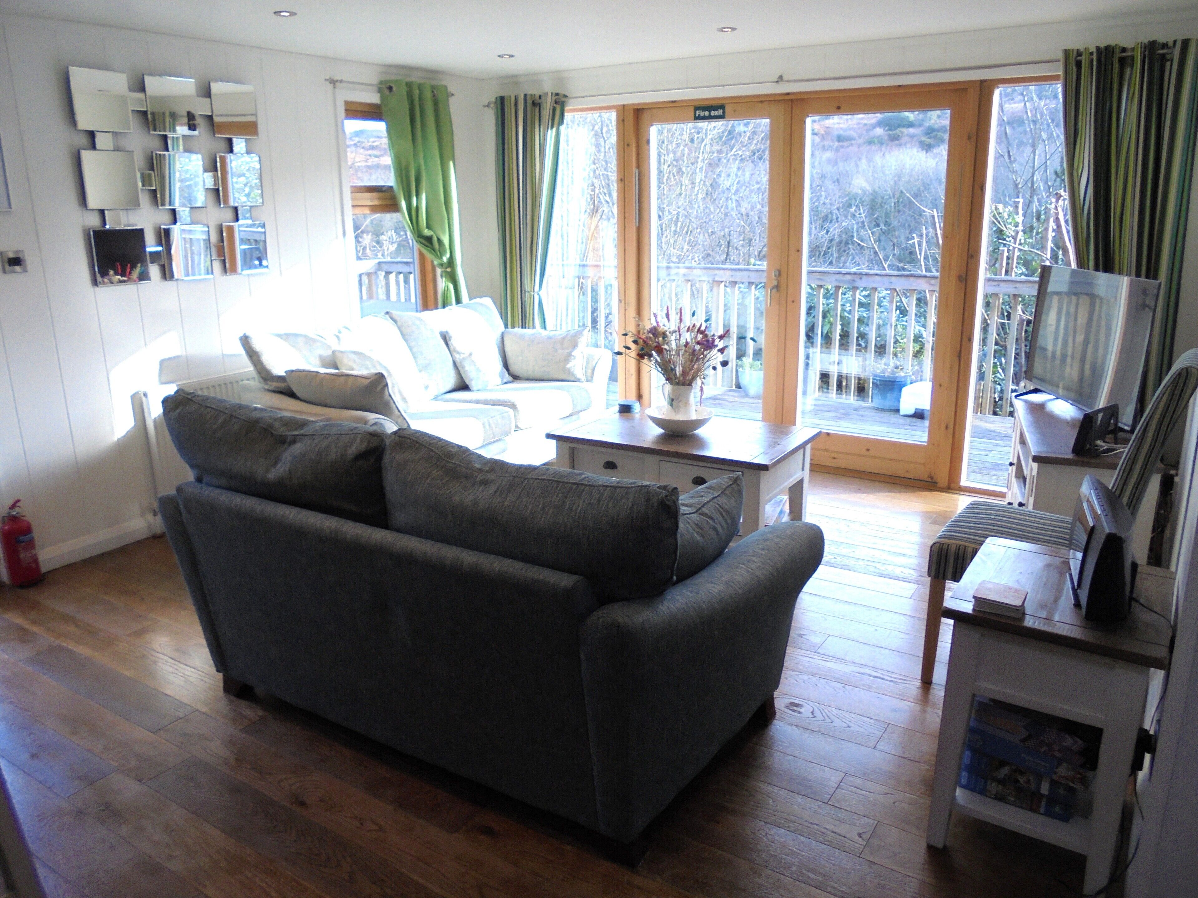 A living room with a grey sofa, a coffee table with a vase, and a television on a stand.