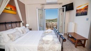 Ein Hotelzimmer mit Bett, kleinem Tisch, Fernseher und Balkon mit Aussicht.
