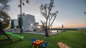 Ein modernes Haus mit Terrasse, Rutsche und Tisch mit Stühlen.