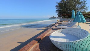 A beachside lounge area with white lounge chairs and green umbrellas, a woven basket, and a view of the ocean. - My Resort Huahin by Love Huahin (Hua Hin)