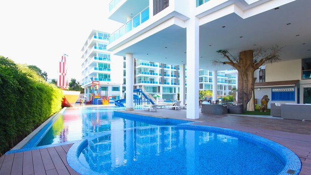 A modern hotel with a large outdoor swimming pool, a children's play area, and a multi-story building with balconies. - My Resort Huahin by Love Huahin (Hua Hin)
