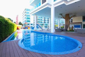 A modern hotel with a large outdoor swimming pool, a children's play area, and a multi-story building with balconies. - My Resort Huahin by Love Huahin (Hua Hin)