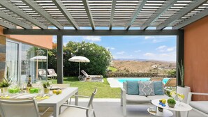 Une terrasse avec une piscine, des sièges d’extérieur et une vue sur le paysage.