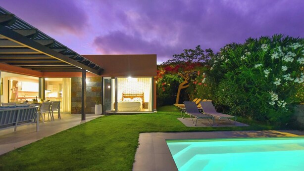 Une maison moderne dotée d’une piscine, d’une terrasse avec des chaises et d’une pelouse bien entretenue.