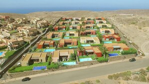 Un quartier résidentiel où les maisons sont alignées en rangées, avec de petits jardins devant et une route au premier plan.