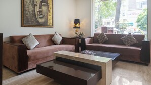 A modern living room with two sofas, a coffee table, and a lamp. -  The Grand Vikalp by Saga Hotels (New Delhi)