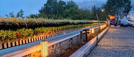 A paved pathway with a stone wall and a white picket fence.