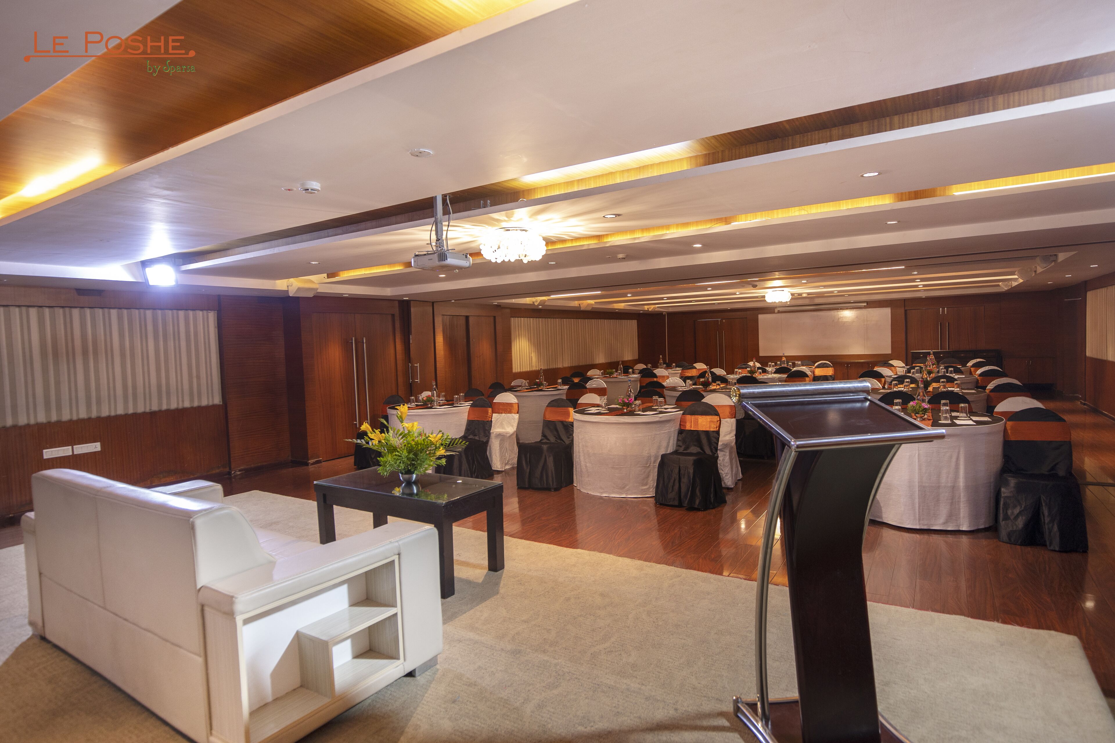 A conference room with round tables, chairs, and a podium.