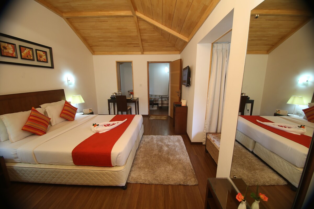 Habitación de hotel con dos camas, techo de madera, un pequeño escritorio y un espejo.