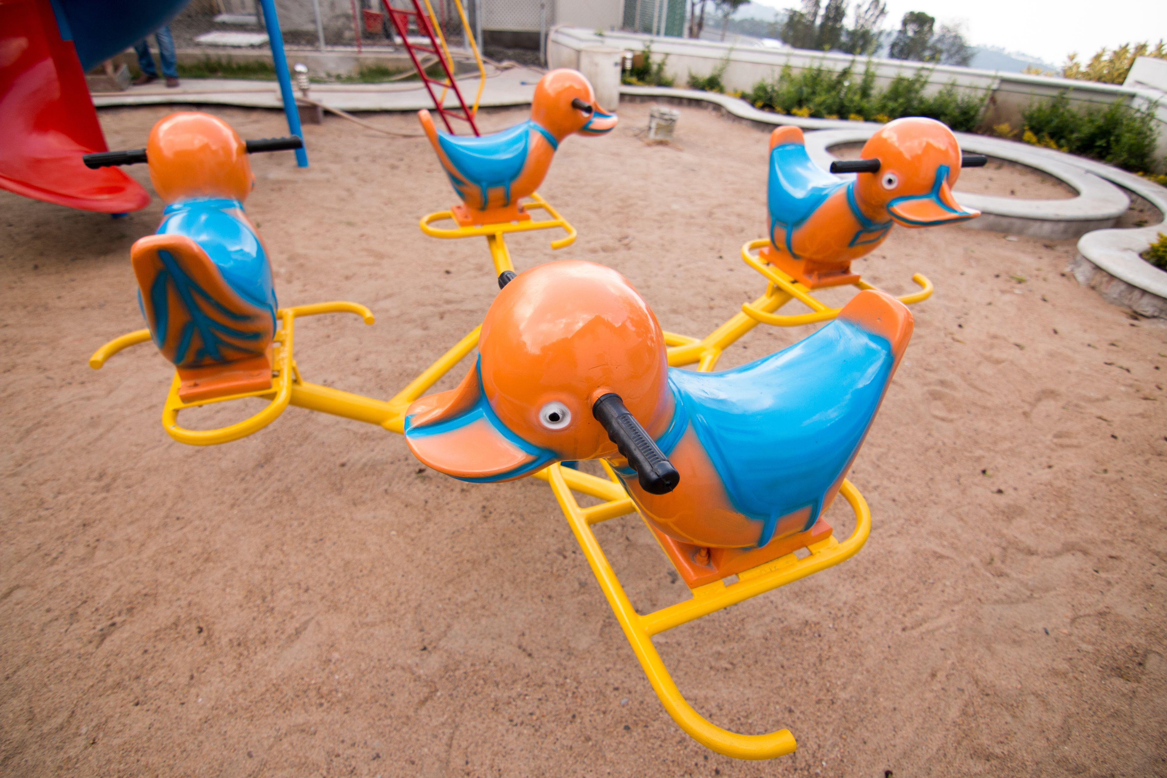 Un parque infantil con tres columpios con forma de elefante, naranja y azul.
