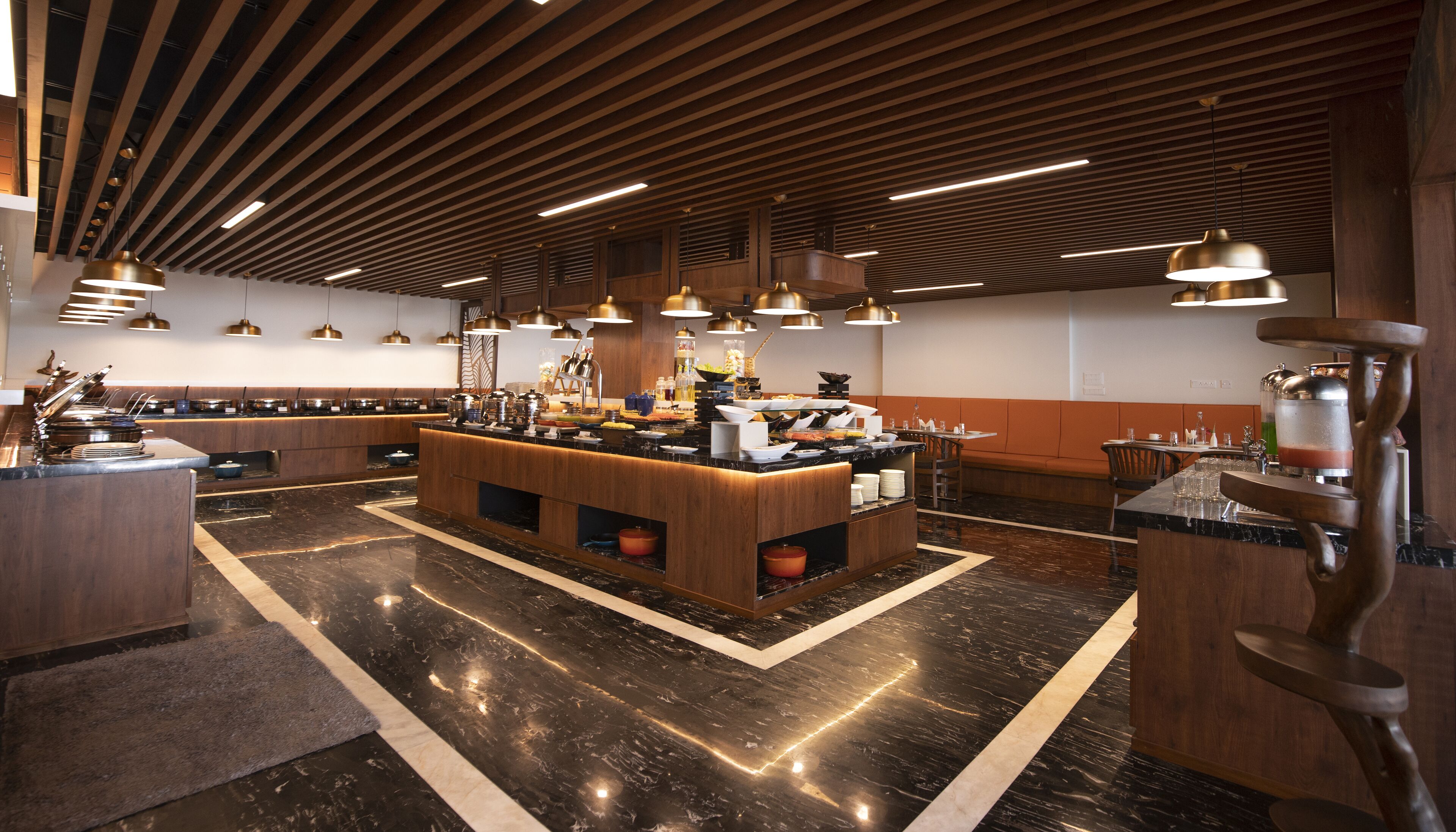 A modern kitchen with a central island, wooden paneling, and pendant lighting.