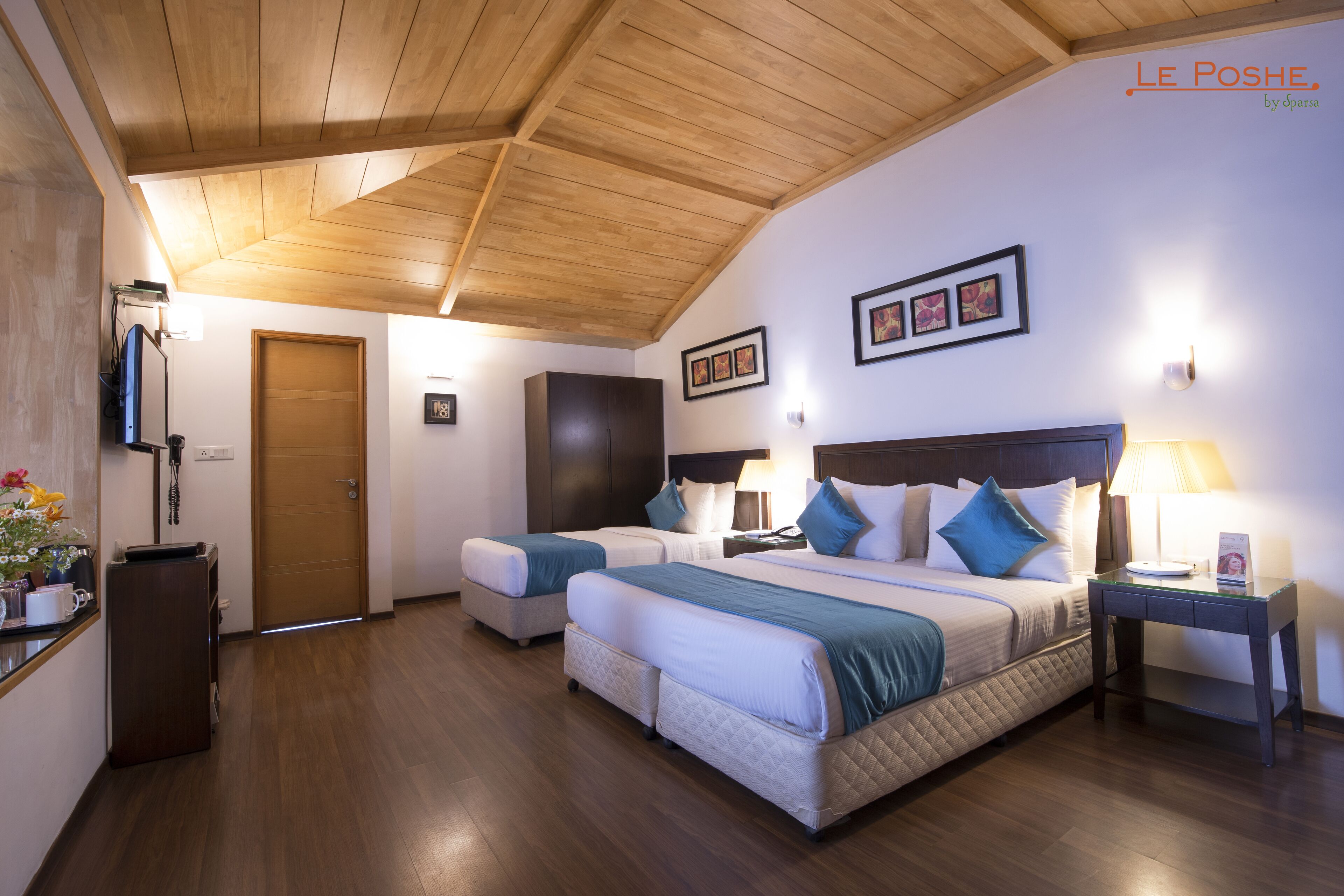 A hotel room with two beds, wooden flooring, a wooden ceiling, and framed pictures on the walls.