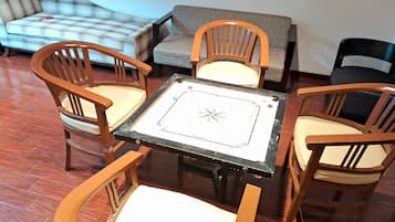 A room with a square table, four wooden chairs, a sofa, and a patterned rug.