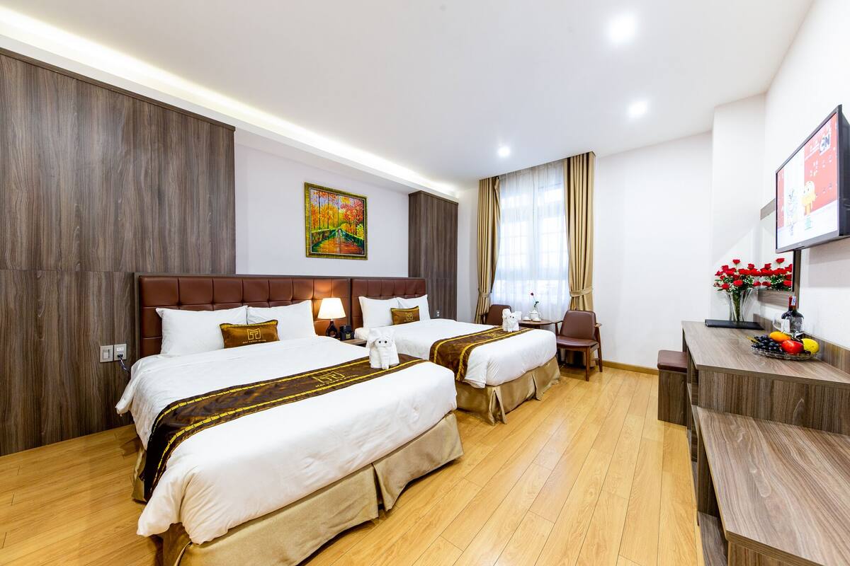 Habitación de hotel con dos camas, un escritorio, una silla y un televisor.