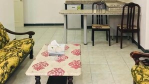 Um espaço compacto com cozinha compacta, dois sofás estampados, uma mesinha e uma cadeira.