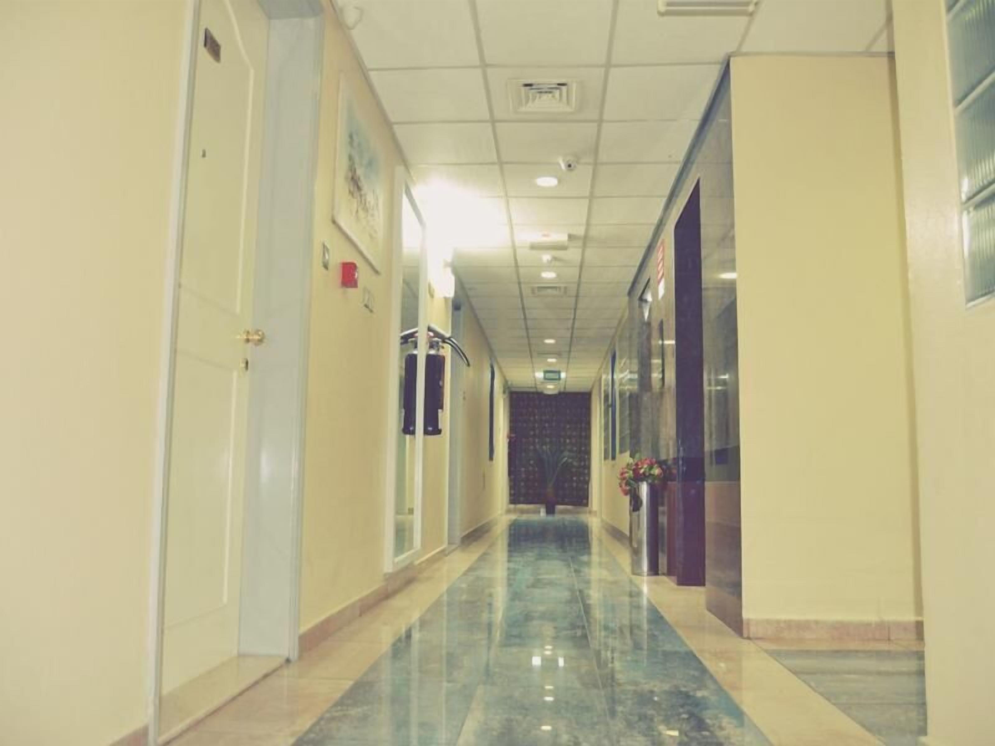 A hallway with a polished floor, doors on the left, and a window on the right.