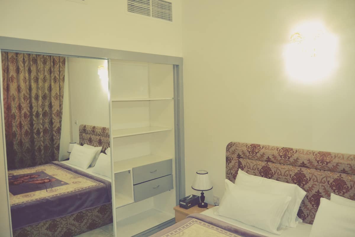 Une chambre à coucher comprenant un lit, une table de chevet, un miroir et une armoire.