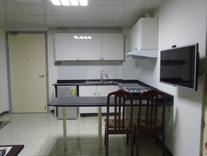 A compact kitchen with a single sink, a stove, and cabinets. There is a dining table with two chairs. - Sky Hotel Apartments (Dubai)