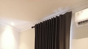 A hotel room with a desk, chair, and a large window with dark curtains. - Hotel Bugis Asri (Yogyakarta)