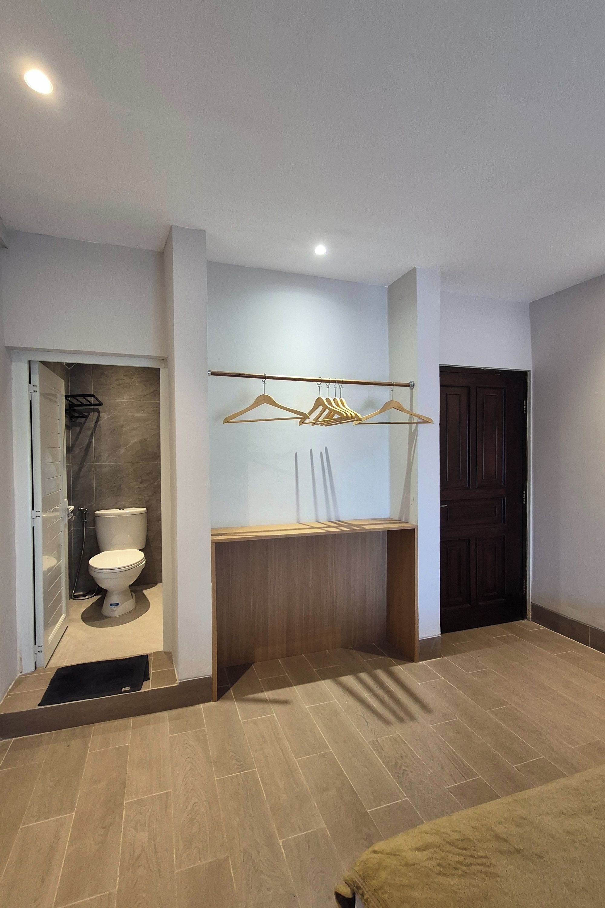 A bathroom with a toilet, a shower, and a wooden vanity with a towel rack.
