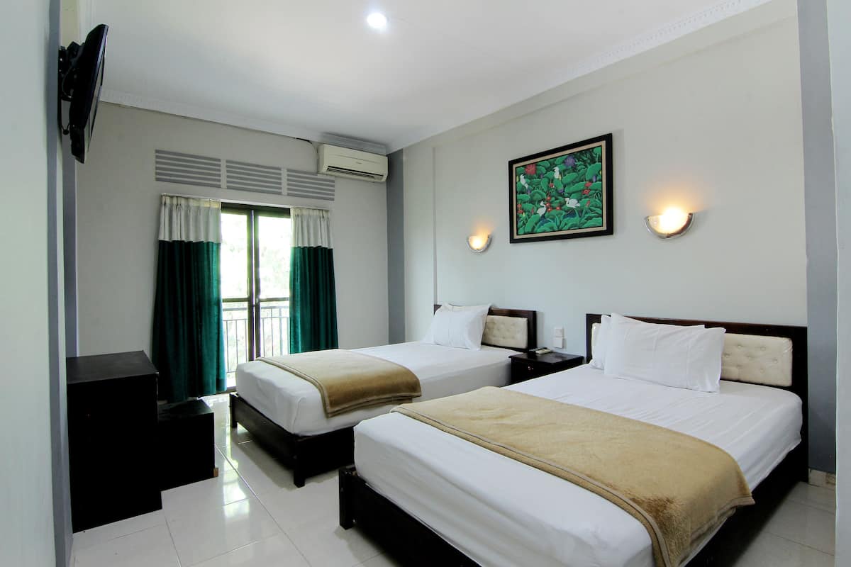 Habitación de hotel con dos camas, un escritorio, un televisor y una ventana con cortinas.