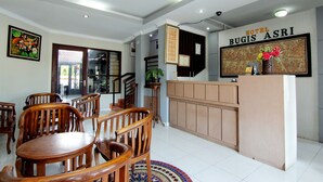 A hotel reception area with wooden furniture, a reception desk, and a large framed artwork on the wall. - Hotel Bugis Asri (Yogyakarta)