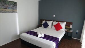 A neatly made bed with white sheets, a purple and black striped blanket, and two rolled towels. - The Backwaters (Eluwankulama)