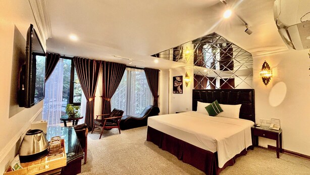 A hotel room with a bed, a desk with a telephone, a chair, and a window with curtains. - Dinh Ami Hanoi Hotel (Hanoi)